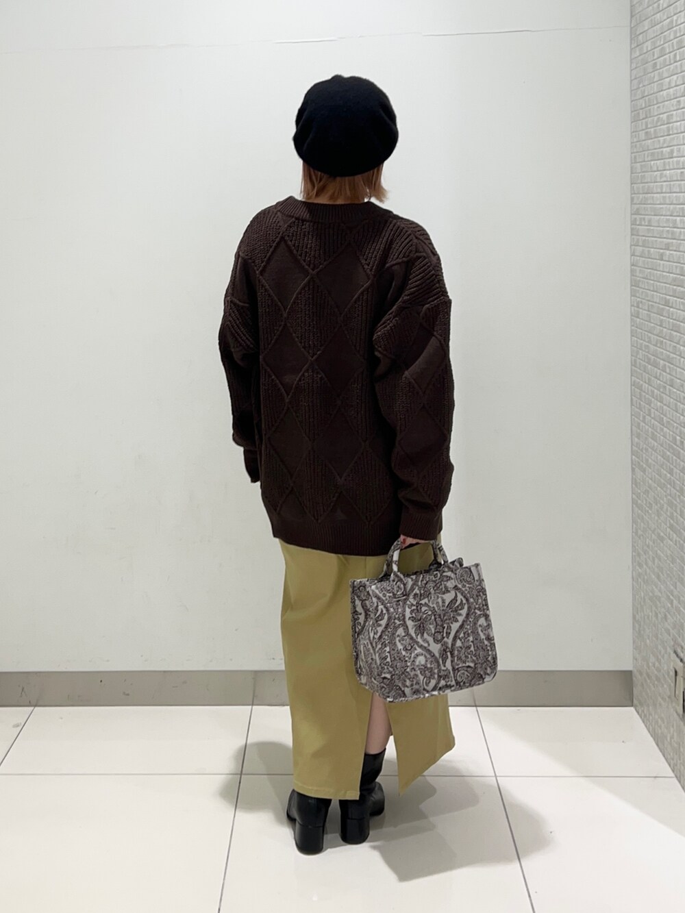 ベージュ系のトートバッグ、ブラック系のブーツ、イエロー系のスカートを着用したレディースの秋コーディネートの4枚目の写真