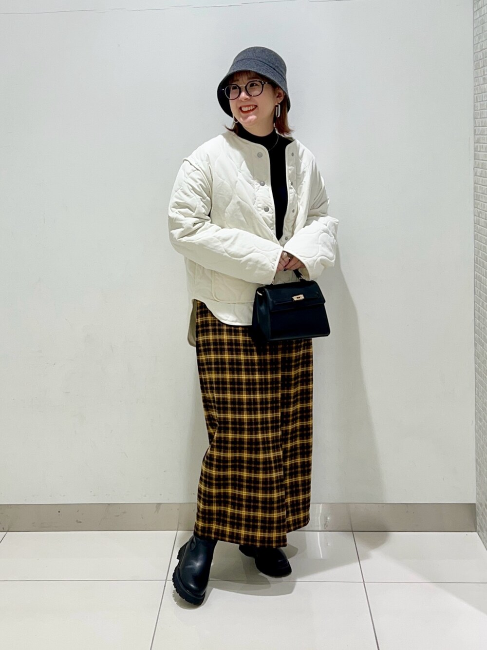 ホワイト系のジャケット/アウター、ブラック系のニット/セーター、イエロー系のスカートを着用したレディースの冬コーディネートの6枚目の写真