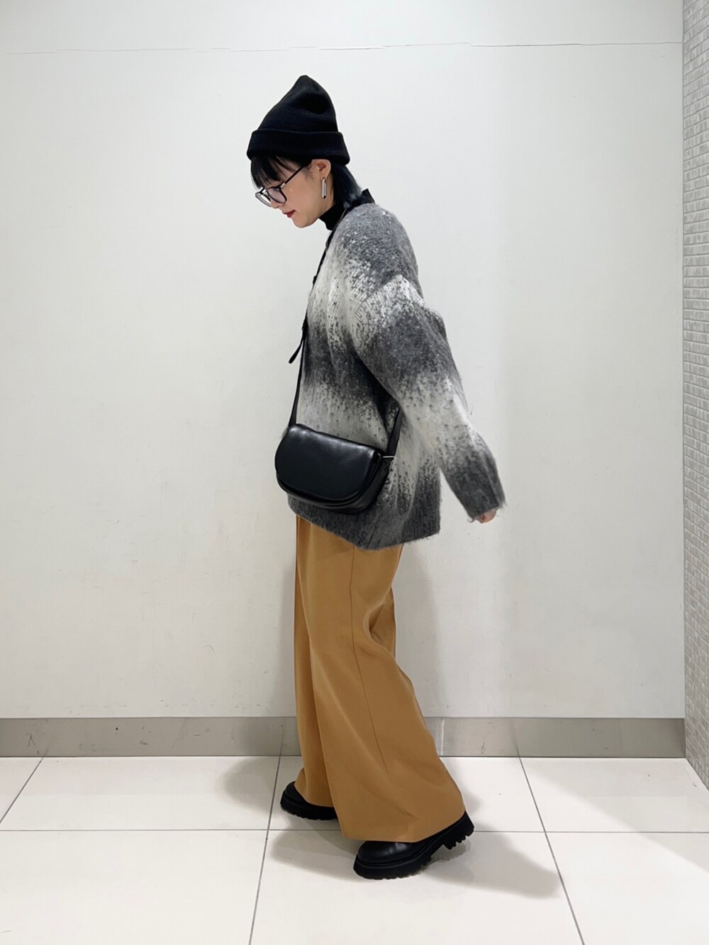 ブラック系のニット/セーター、ブラック系のショルダーバッグ、グレー系のカーディガン/ボレロを着用したレディースの秋コーディネートの3枚目の写真