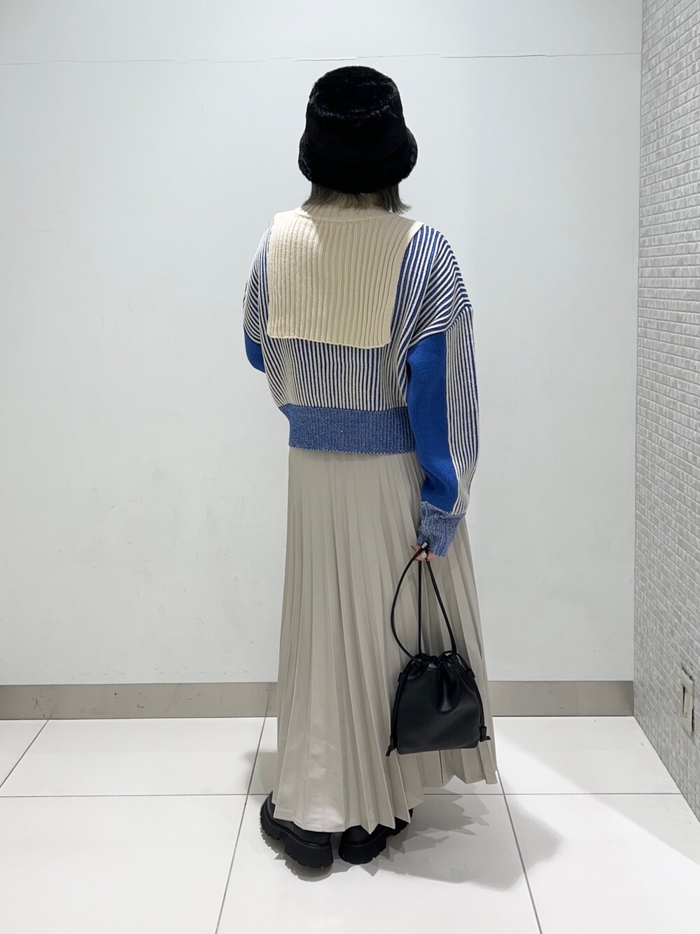 ベージュ系のスカート、ブラック系のショルダーバッグ、ブラック系のブーツを着用したレディースの秋コーディネートの4枚目の写真