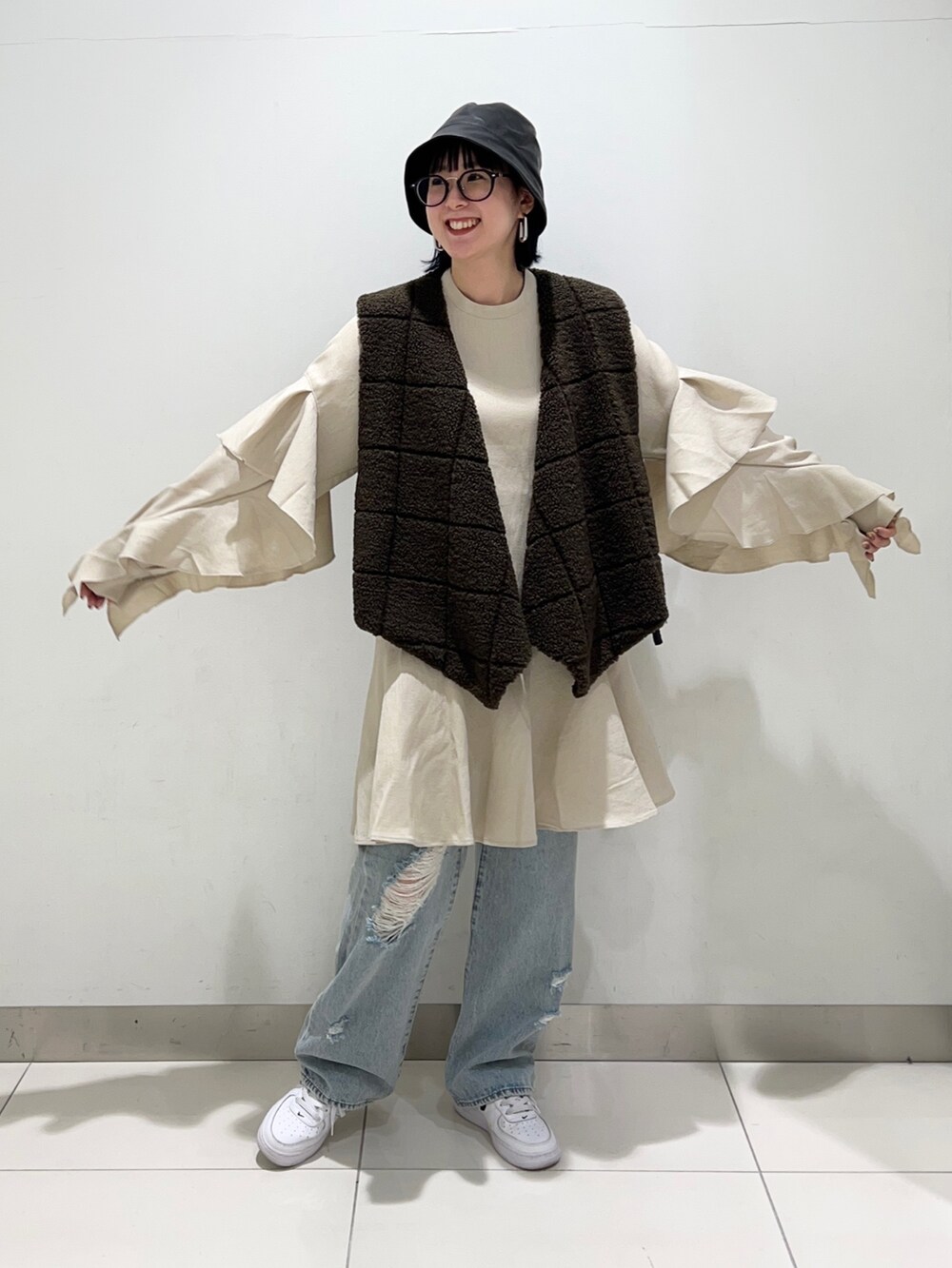 ブラウン系のベスト、ベージュ系のワンピース/ドレス、ブルー系のデニムパンツを着用したレディースの秋コーディネートの7枚目の写真