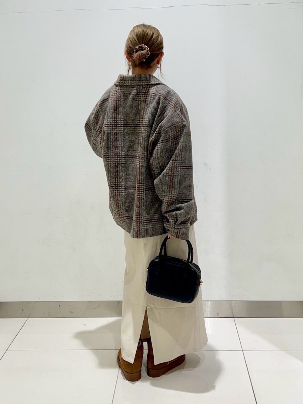 ブラック系のボストンバッグ、ベージュ系のスカート、ブラック系のニット/セーターを着用したレディースの冬コーディネートの4枚目の写真