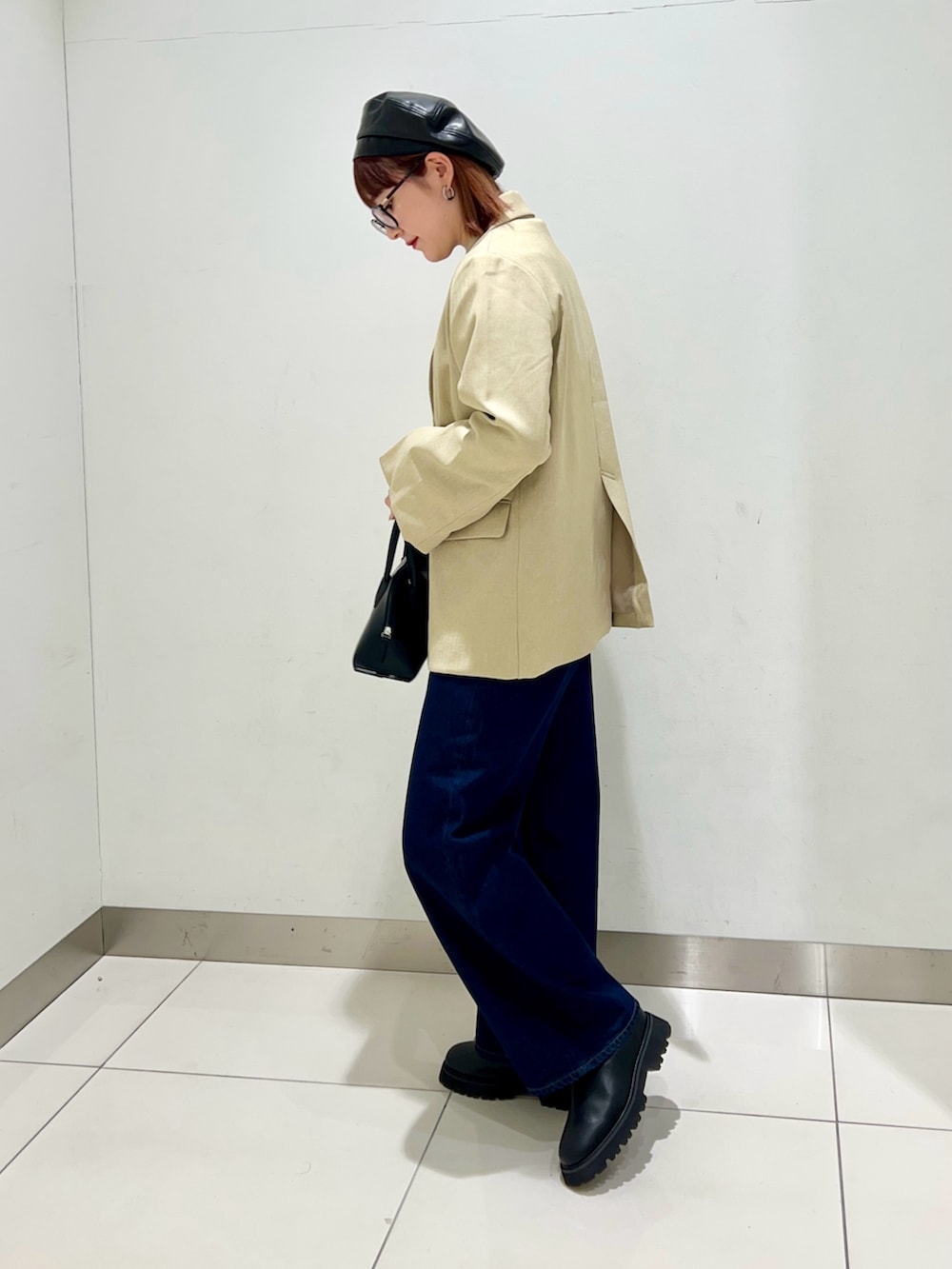 ブラック系のブーツ、ブルー系のデニムパンツ、ブラック系のショルダーバッグを着用したレディースの冬コーディネートの3枚目の写真