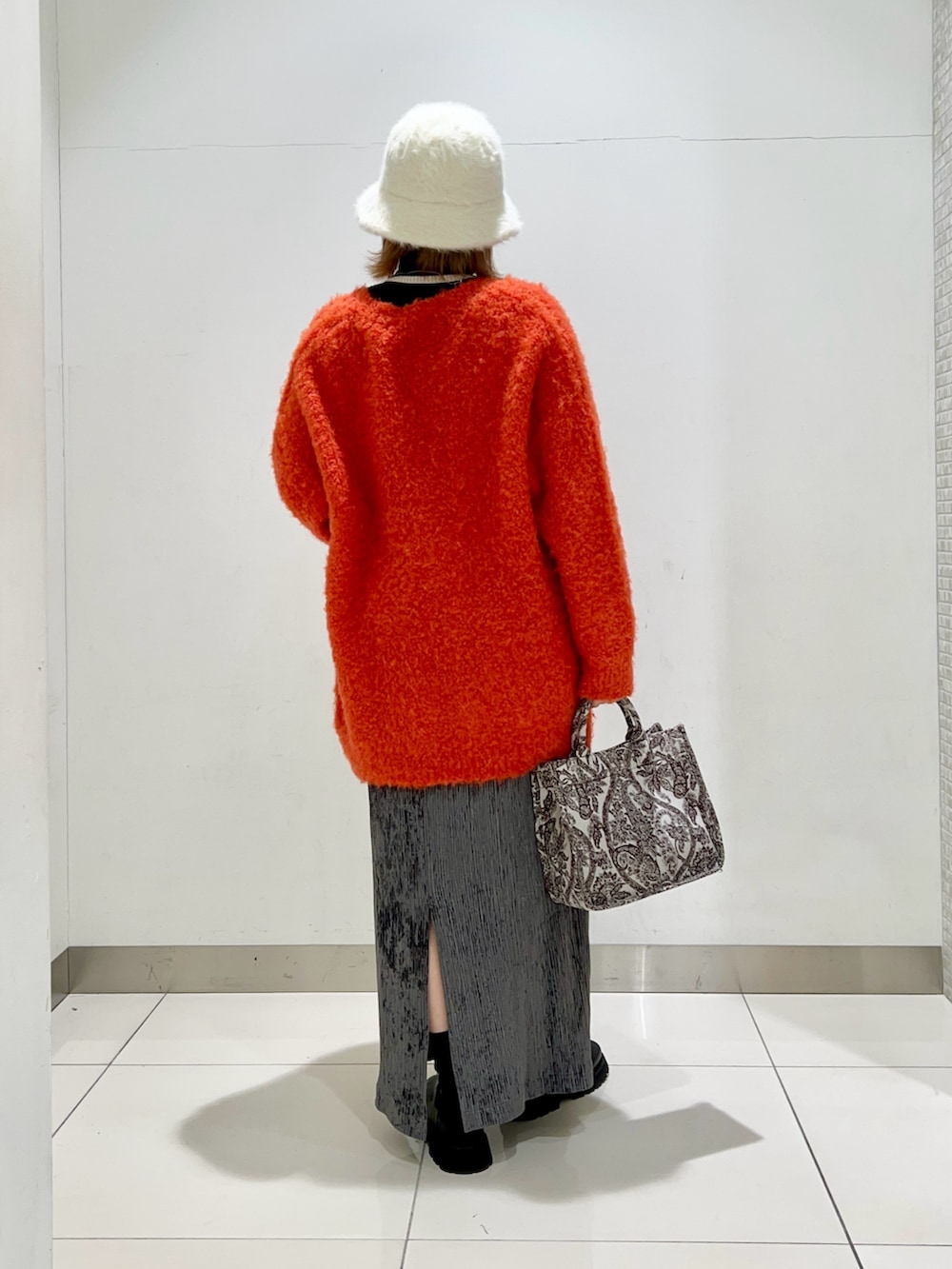 ブラック系のニット/セーター、オレンジ系のカーディガン/ボレロ、ブラウン系のトートバッグを着用したレディースの冬コーディネートの4枚目の写真