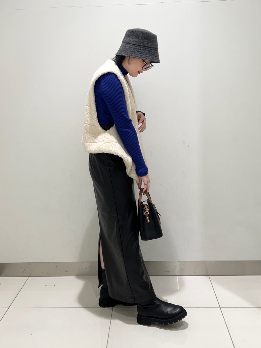 ホワイト系のベスト、ブラック系のスカート、ブルー系のニット/セーターを着用したレディースの秋コーディネートの5枚目の写真