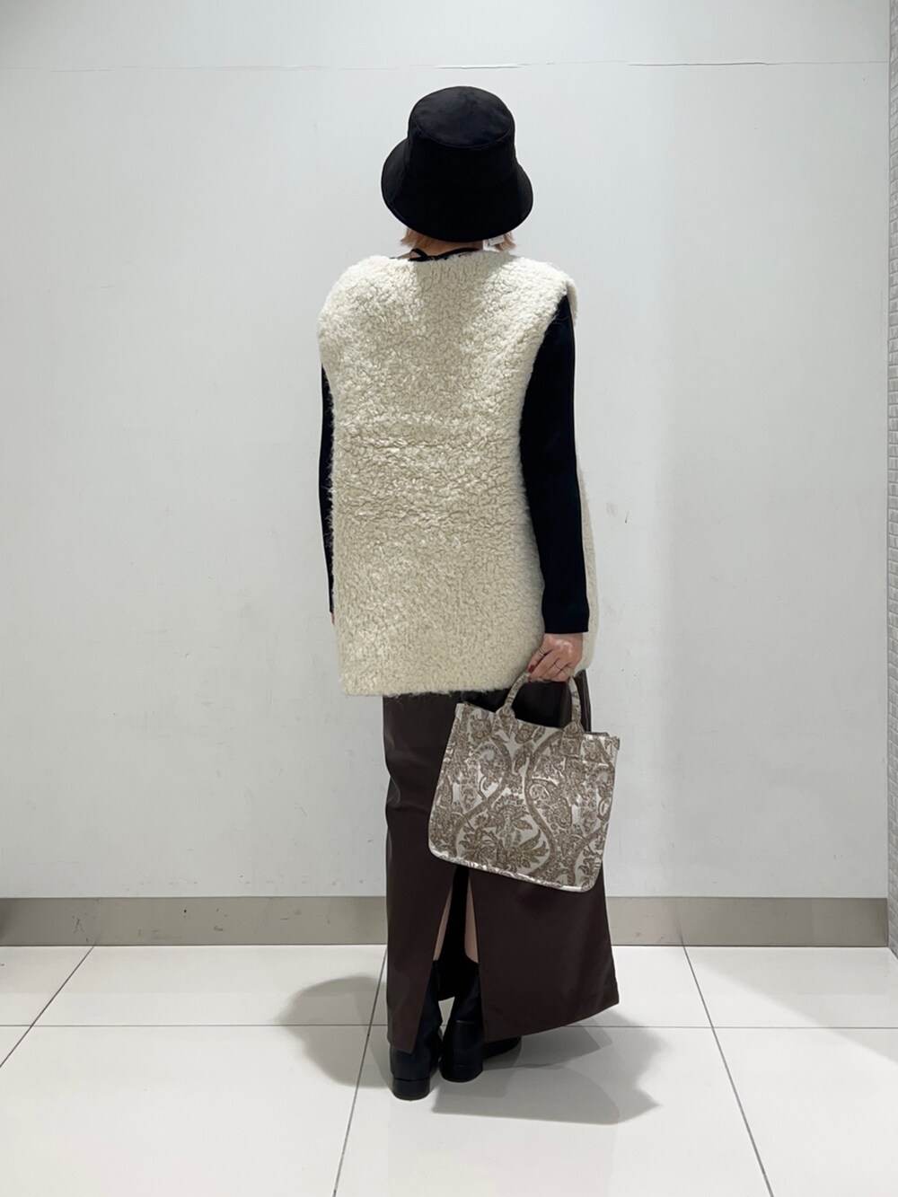 ベージュ系のトートバッグ、ブラック系のニット/セーター、ブラウン系のスカートを着用したレディースの秋コーディネートの4枚目の写真