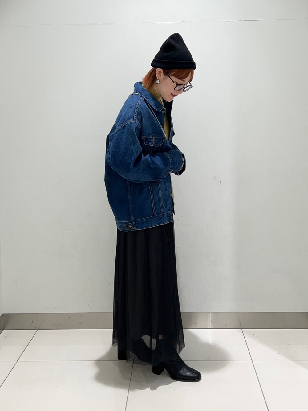 ブラック系のスカート、ブルー系のデニムジャケット、イエロー系のニット/セーターを着用したレディースの秋コーディネートの5枚目の写真