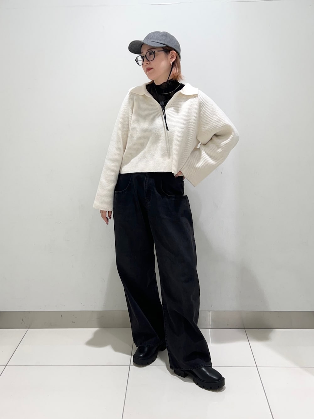 ブラック系のデニムパンツ、ブラック系のブーツ、ホワイト系のニット/セーターを着用したレディースの秋コーディネートの2枚目の写真