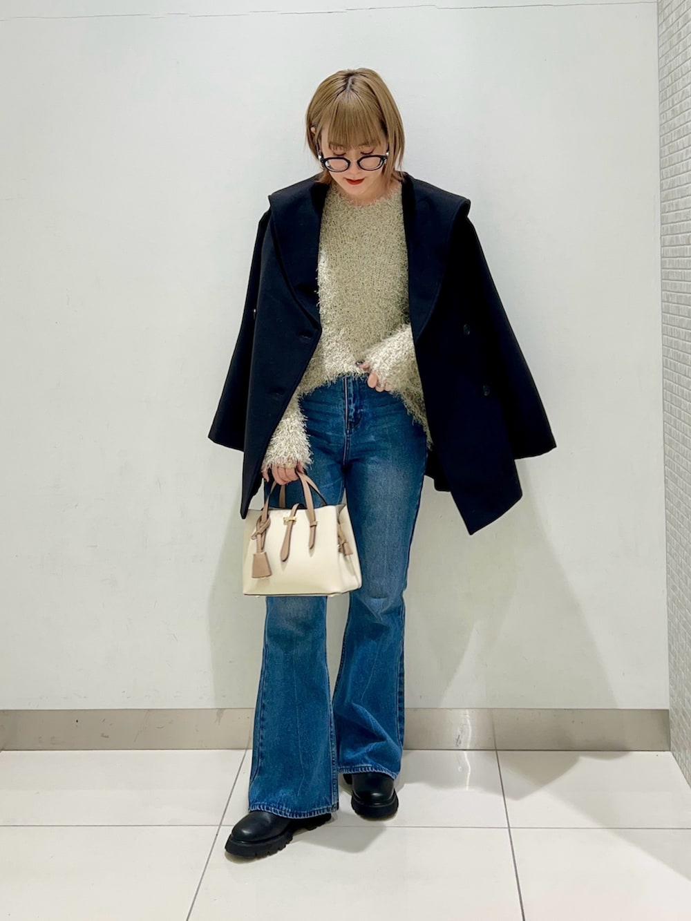 ブラック系のブーツ、ホワイト系のハンドバッグ、ブラック系のその他アウターを着用したレディースの冬コーディネートの2枚目の写真