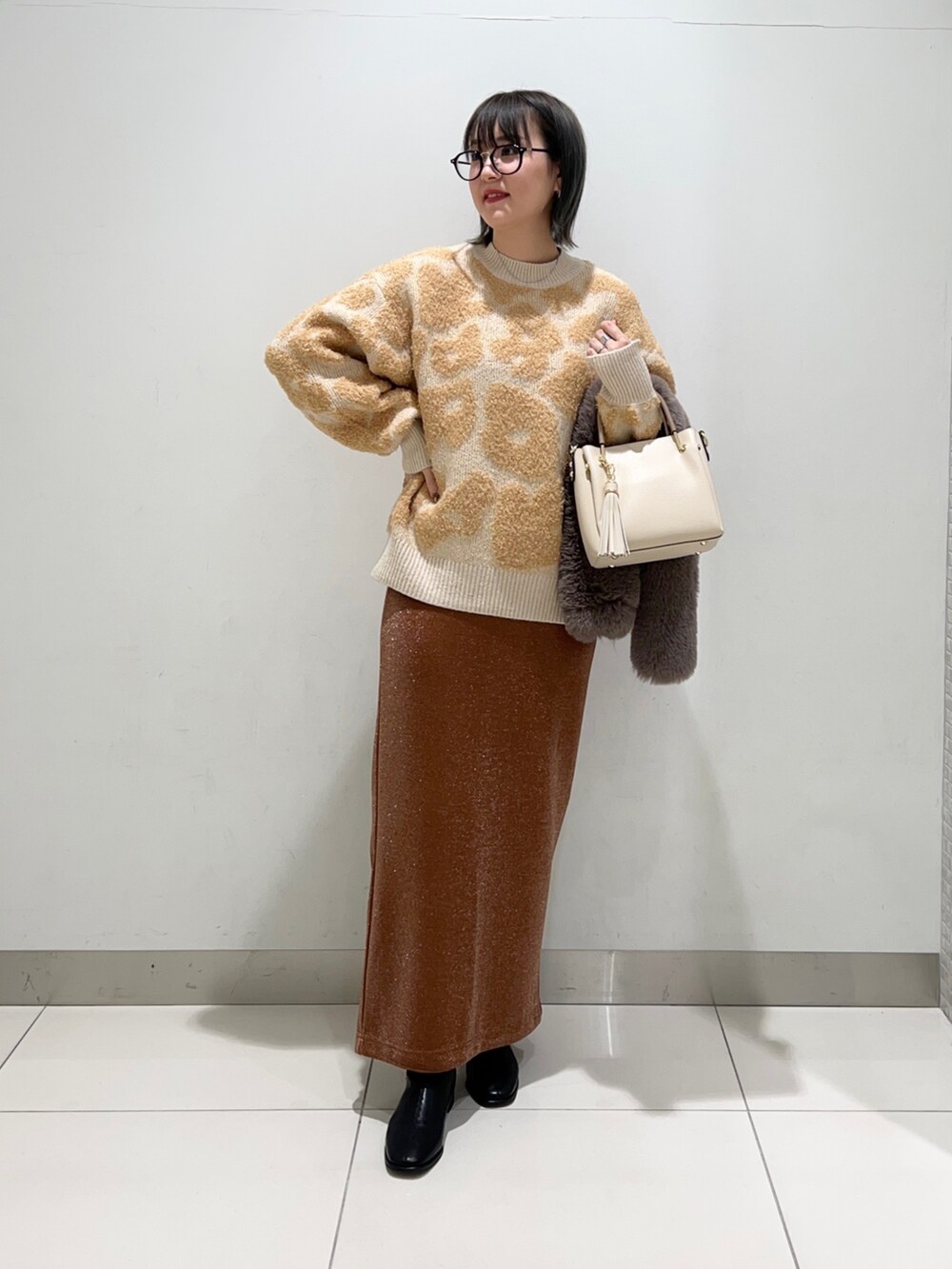 ブラック系のブーツ、ホワイト系のトートバッグ、ブラウン系のスカートを着用したレディースの秋コーディネートの7枚目の写真