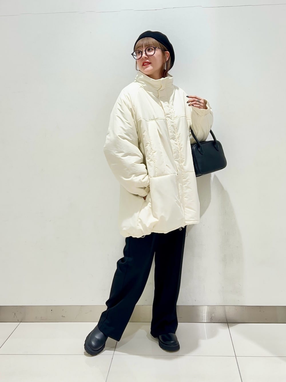 ブラック系のボストンバッグ、ブラック系のスラックス、ブラック系のブーツを着用したレディースの秋コーディネートの2枚目の写真