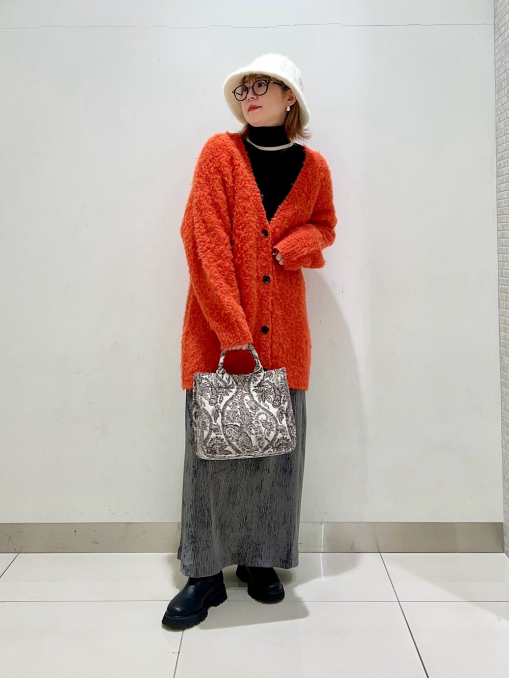 ブラック系のニット/セーター、オレンジ系のカーディガン/ボレロ、ブラウン系のトートバッグを着用したレディースの冬コーディネートの7枚目の写真