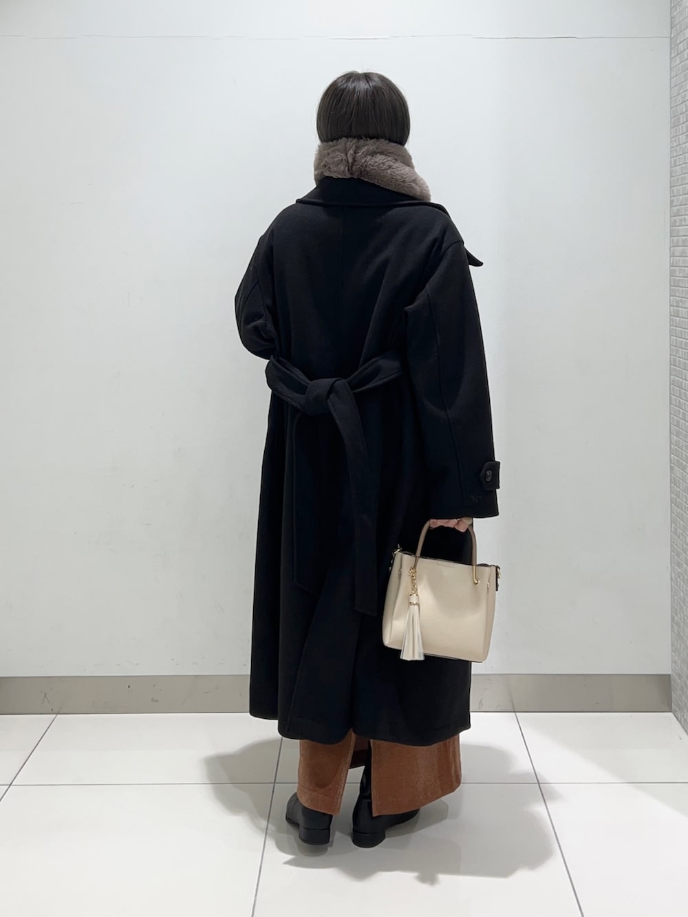 ブラック系のブーツ、ホワイト系のトートバッグ、ブラウン系のスカートを着用したレディースの秋コーディネートの4枚目の写真