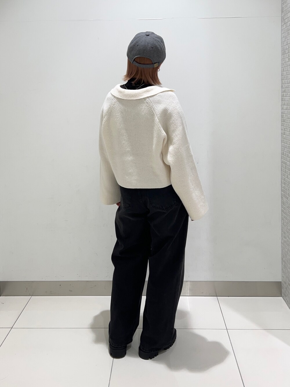 ブラック系のデニムパンツ、ブラック系のブーツ、ホワイト系のニット/セーターを着用したレディースの秋コーディネートの4枚目の写真