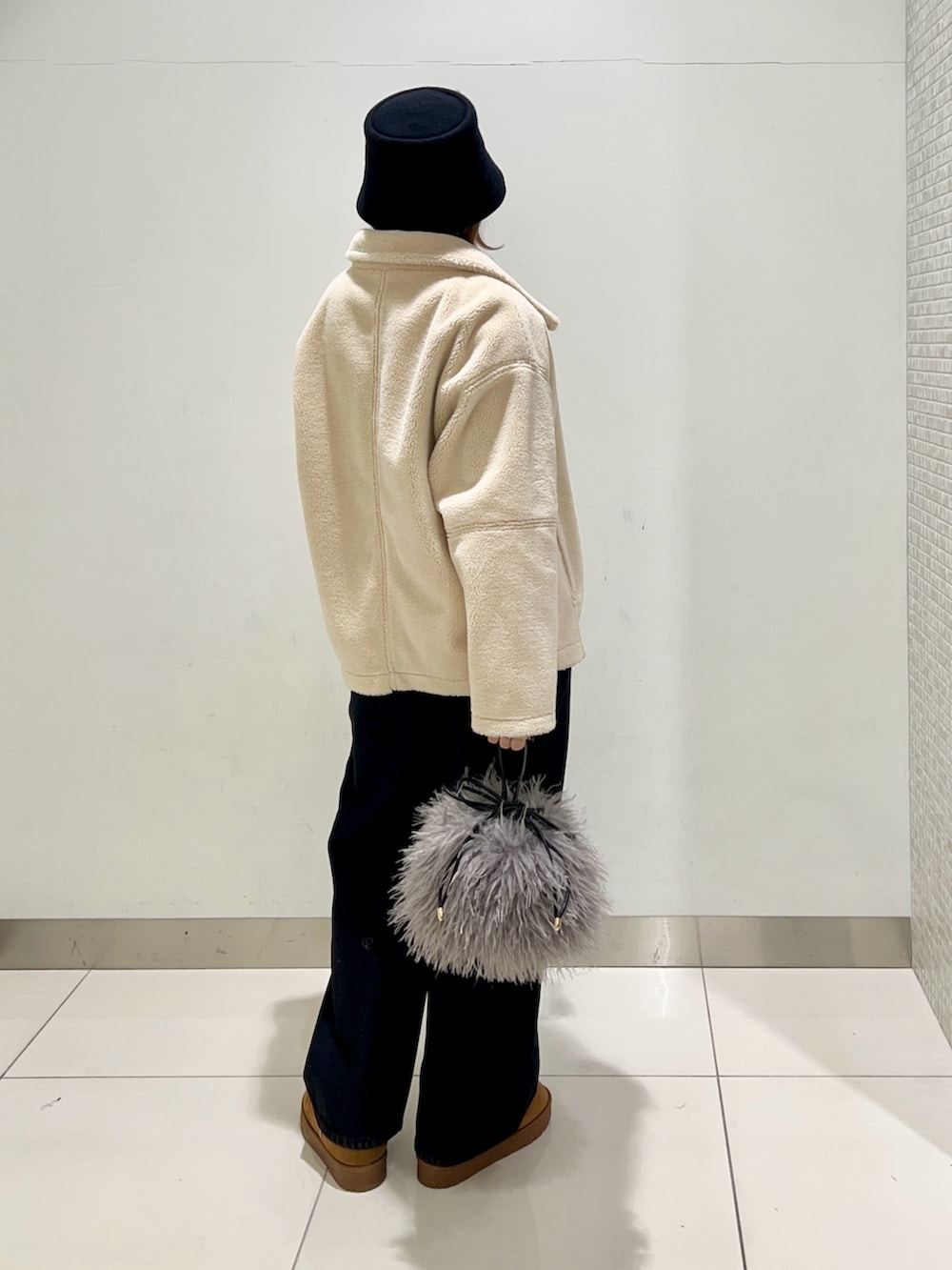 ブラック系のデニムパンツ、ブルー系のニット/セーター、ホワイト系のブルゾンを着用したレディースの冬コーディネートの4枚目の写真