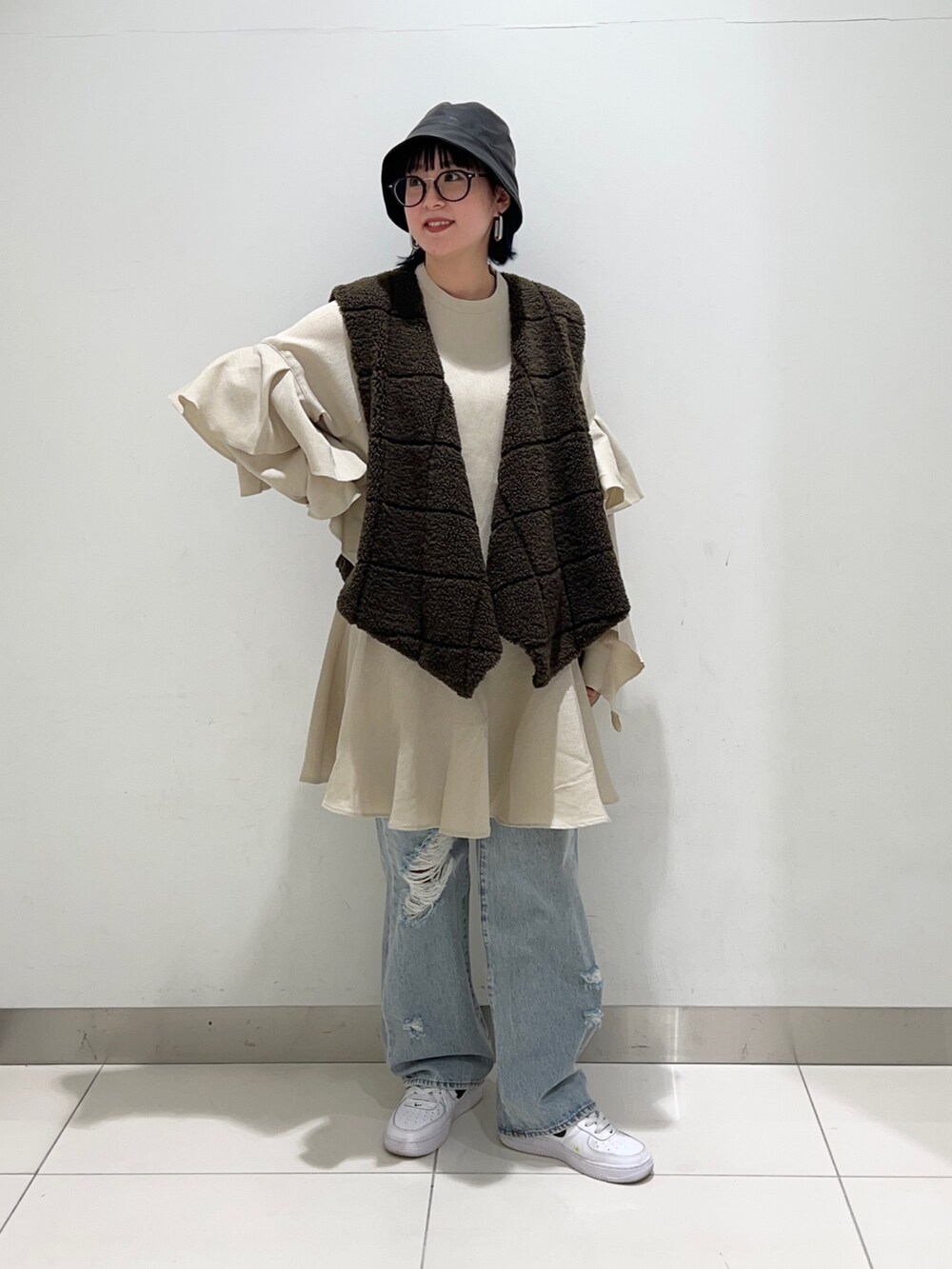 ブラウン系のベスト、ベージュ系のワンピース/ドレス、ブルー系のデニムパンツを着用したレディースの秋コーディネートの6枚目の写真