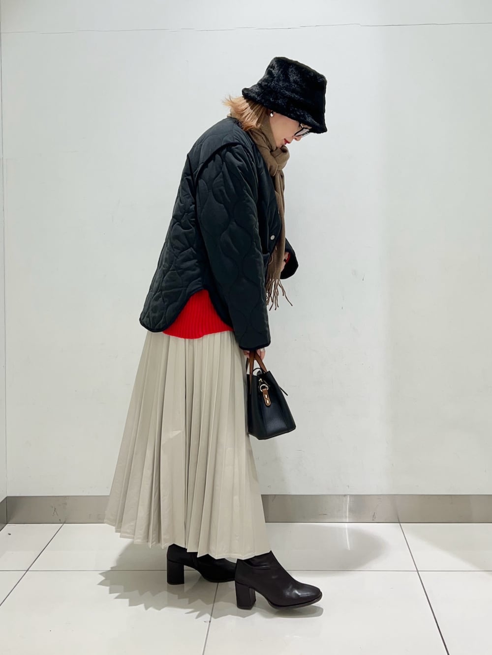 ブラウン系のブーツ、ベージュ系のスカート、ブラック系のハンドバッグを着用したレディースの冬コーディネートの7枚目の写真