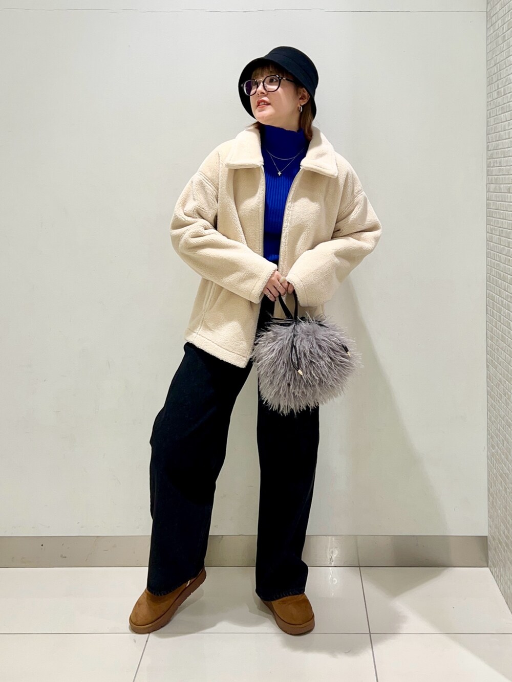 ブラック系のデニムパンツ、ブルー系のニット/セーター、ホワイト系のブルゾンを着用したレディースの冬コーディネートの7枚目の写真