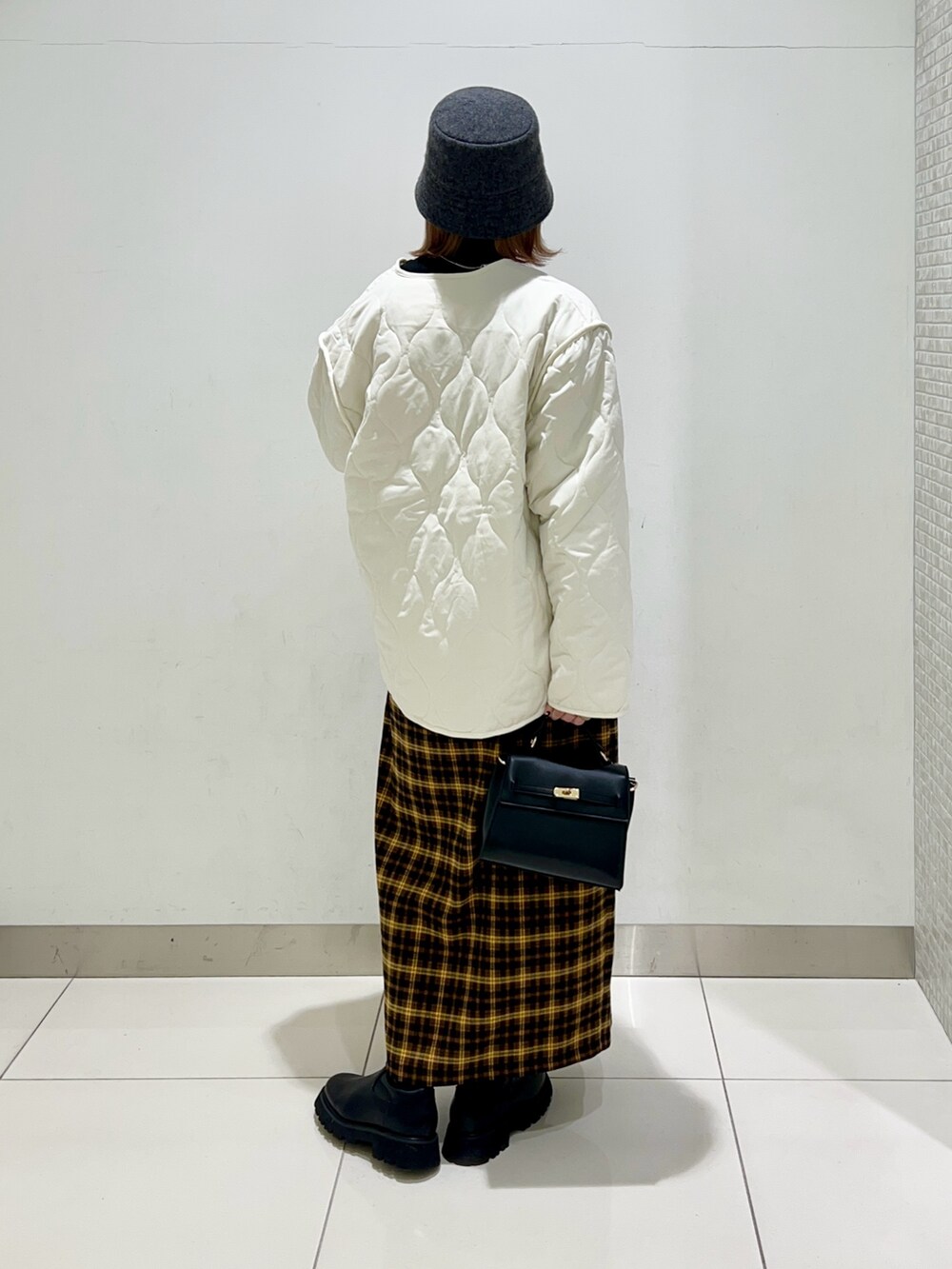 ホワイト系のジャケット/アウター、ブラック系のニット/セーター、イエロー系のスカートを着用したレディースの冬コーディネートの4枚目の写真