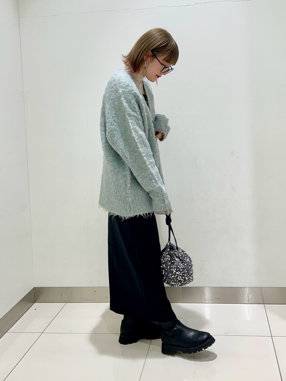 ブルー系のカーディガン/ボレロ、ブラック系のワンピース、ブラック系のブーツを着用したレディースの秋コーディネートの5枚目の写真