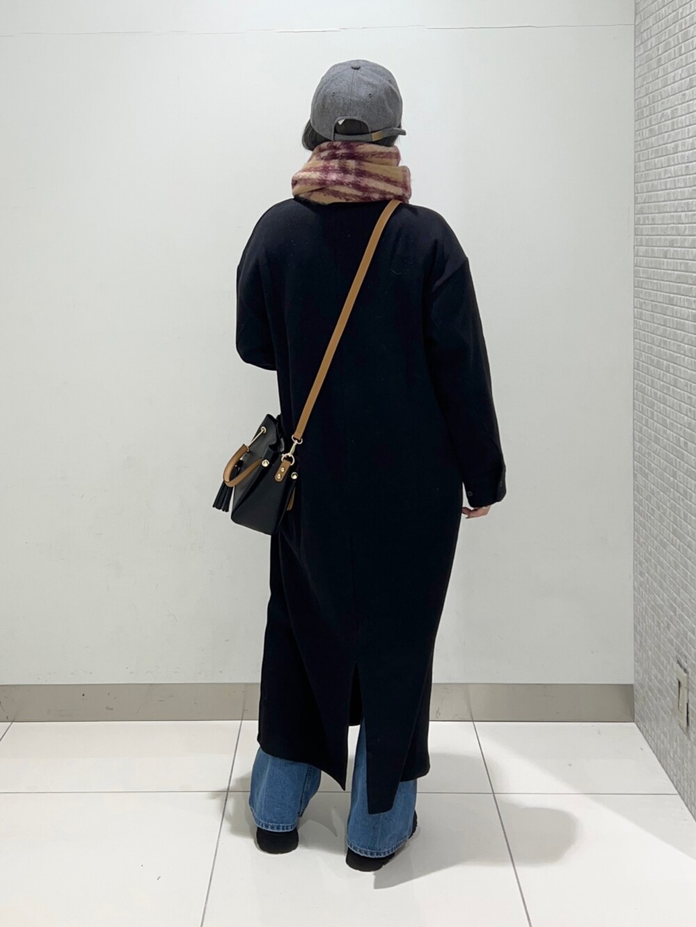 ブラック系のトートバッグ、ブラック系のワンピース、ブラック系のブーツを着用したレディースの秋コーディネートの3枚目の写真