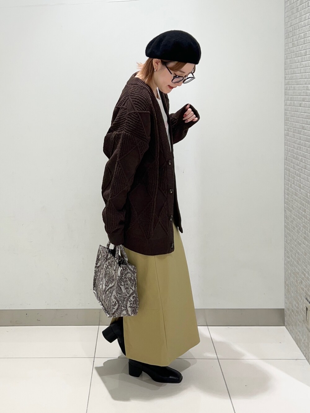 ベージュ系のトートバッグ、ブラック系のブーツ、イエロー系のスカートを着用したレディースの秋コーディネートの5枚目の写真