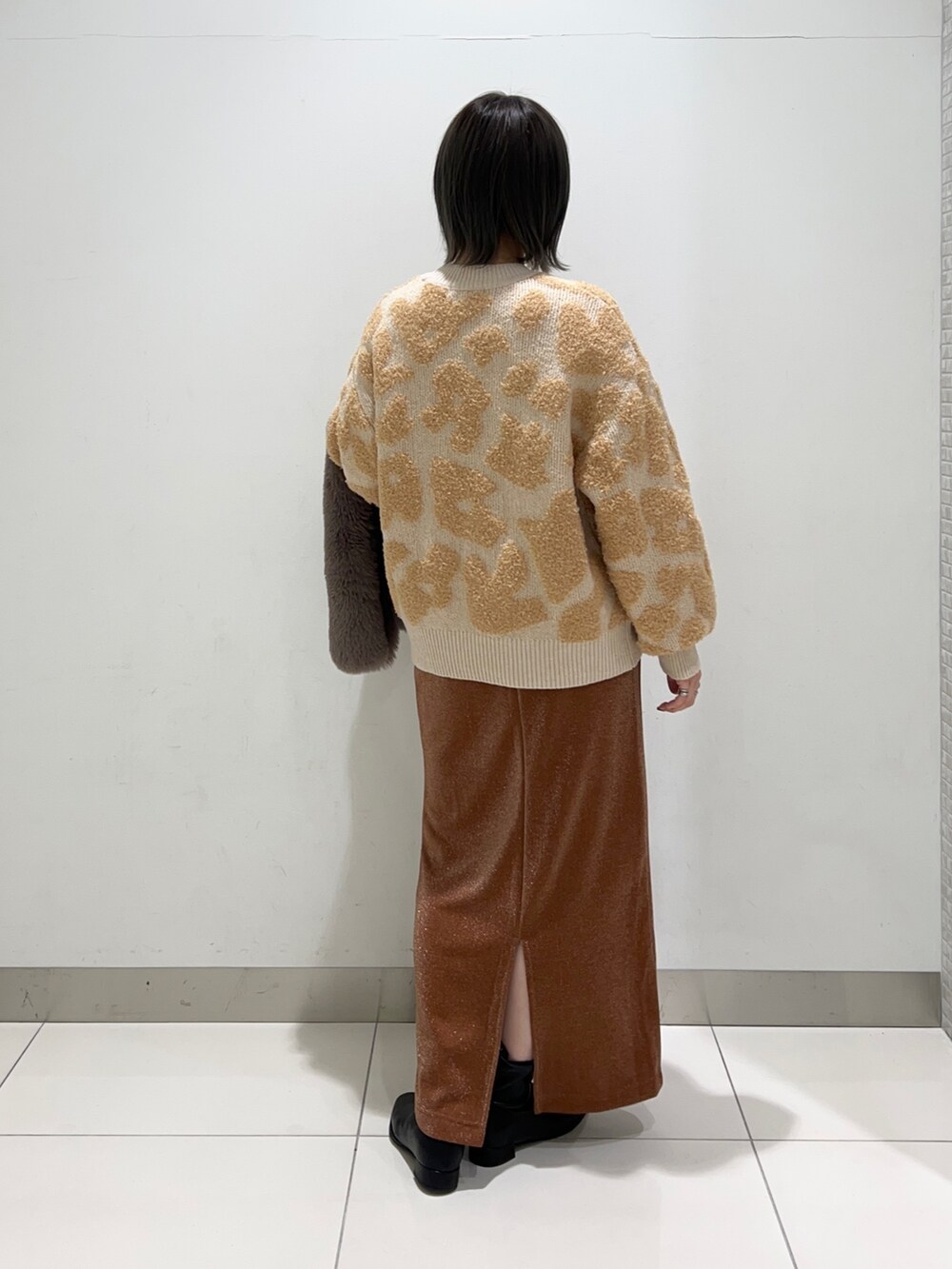 ブラック系のブーツ、ホワイト系のトートバッグ、ブラウン系のスカートを着用したレディースの秋コーディネートの9枚目の写真