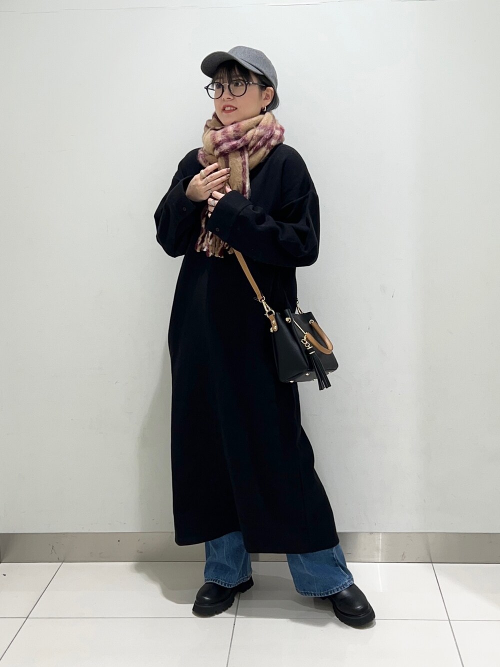 ブラック系のトートバッグ、ブラック系のワンピース、ブラック系のブーツを着用したレディースの秋コーディネートの5枚目の写真