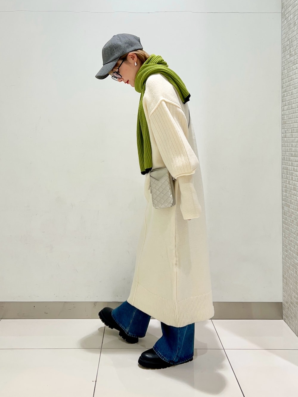 シルバー系のショルダーバッグ、ホワイト系のワンピース、ブルー系のデニムパンツを着用したレディースの冬コーディネートの3枚目の写真