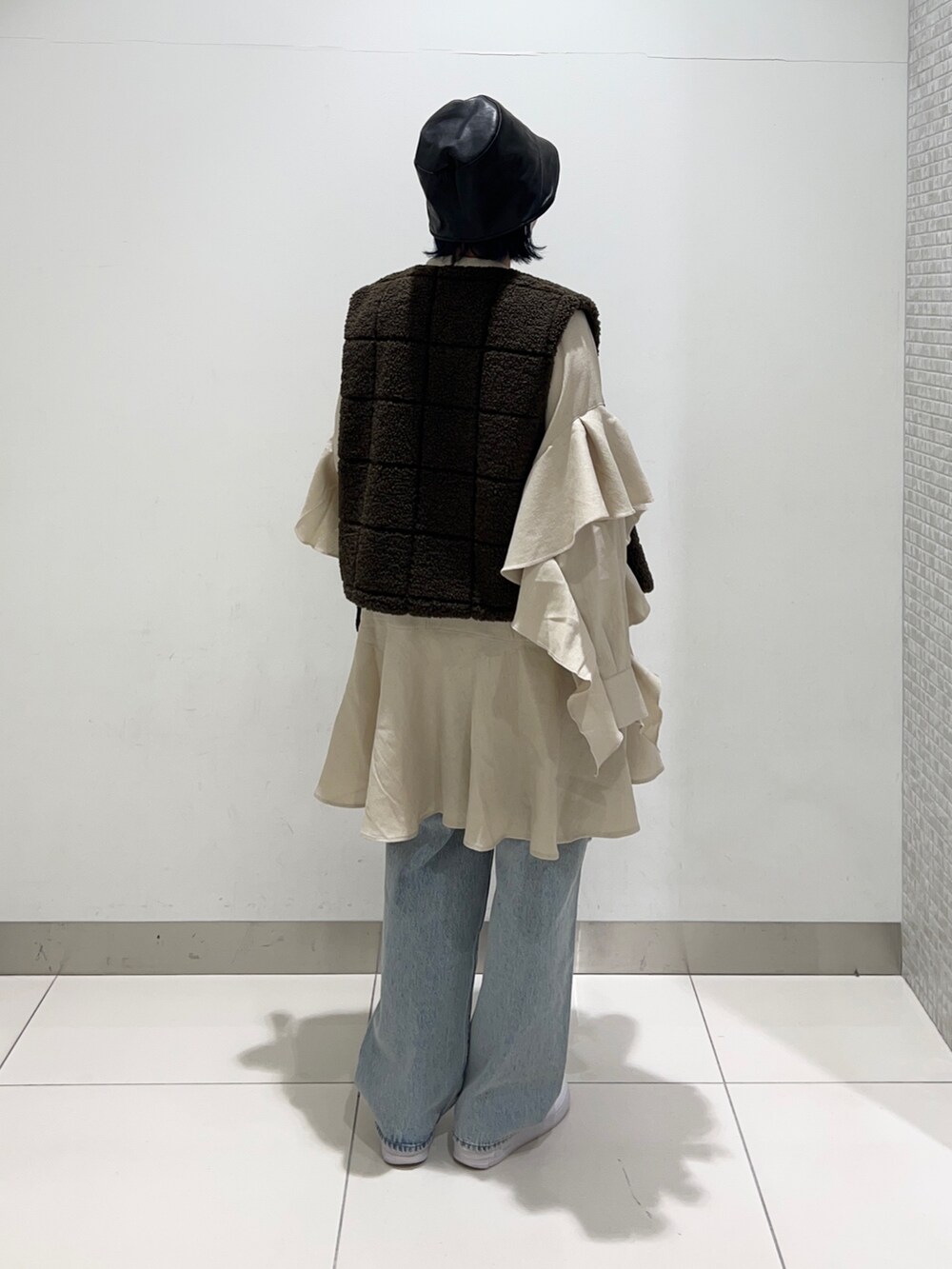 ブラウン系のベスト、ベージュ系のワンピース/ドレス、ブルー系のデニムパンツを着用したレディースの秋コーディネートの4枚目の写真