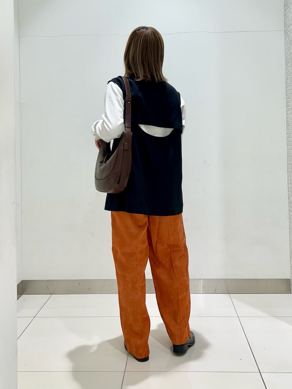 ブラウン系のショルダーバッグ、ブラック系のその他アウター、オレンジ系のその他パンツを着用したレディースの春コーディネートの4枚目の写真