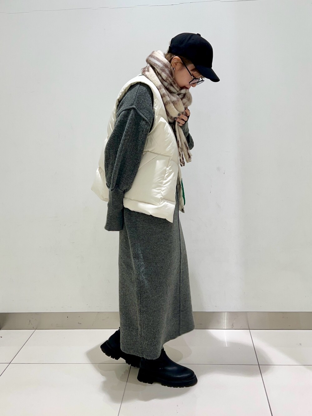 ブラック系のブーツ、グリーン系のショルダーバッグ、ホワイト系のダウンベストを着用したレディースの秋コーディネートの5枚目の写真