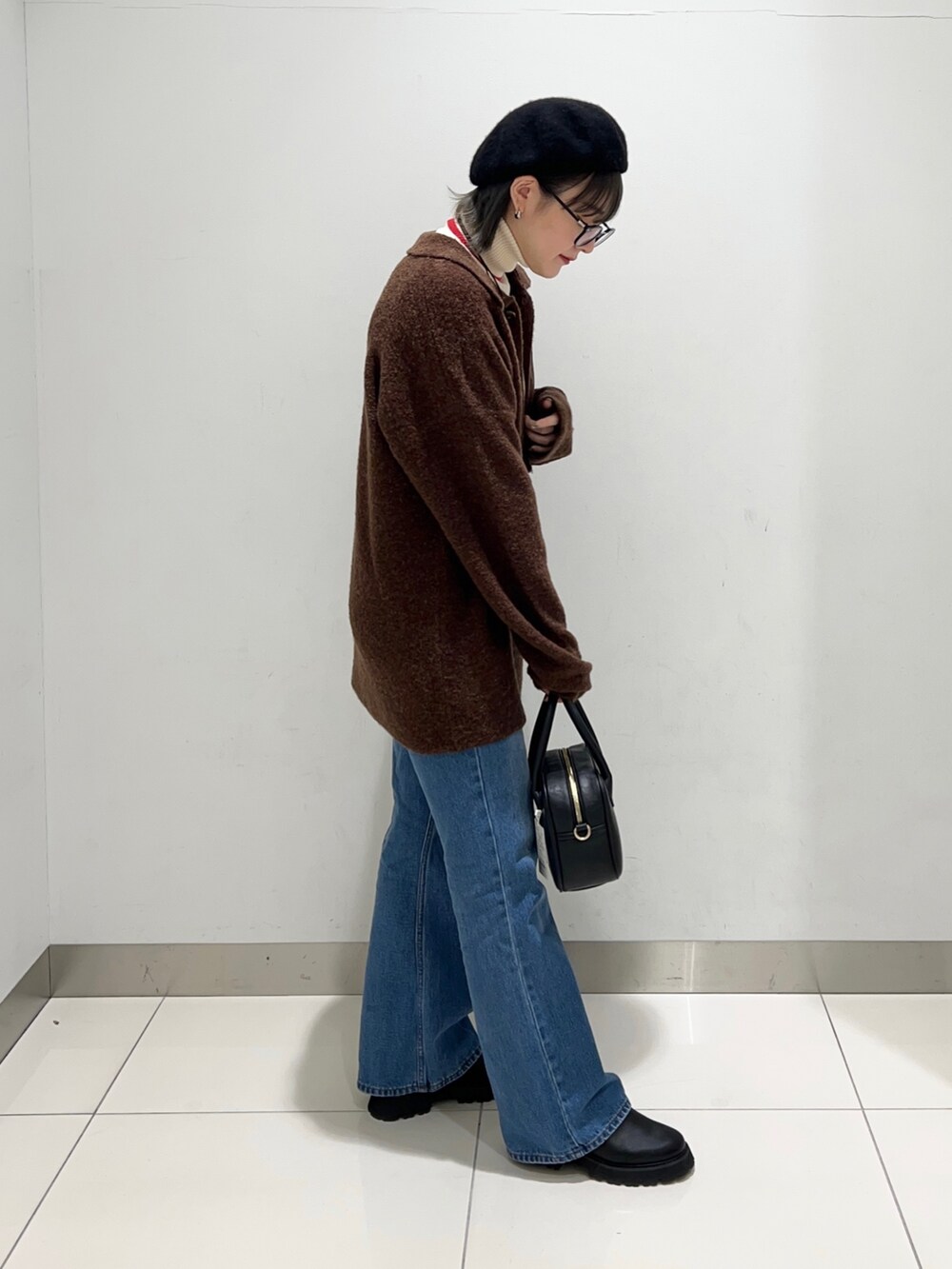 ブラック系のブーツ、ブルー系のデニムパンツ、ブラック系のボストンバッグを着用したレディースの秋コーディネートの5枚目の写真