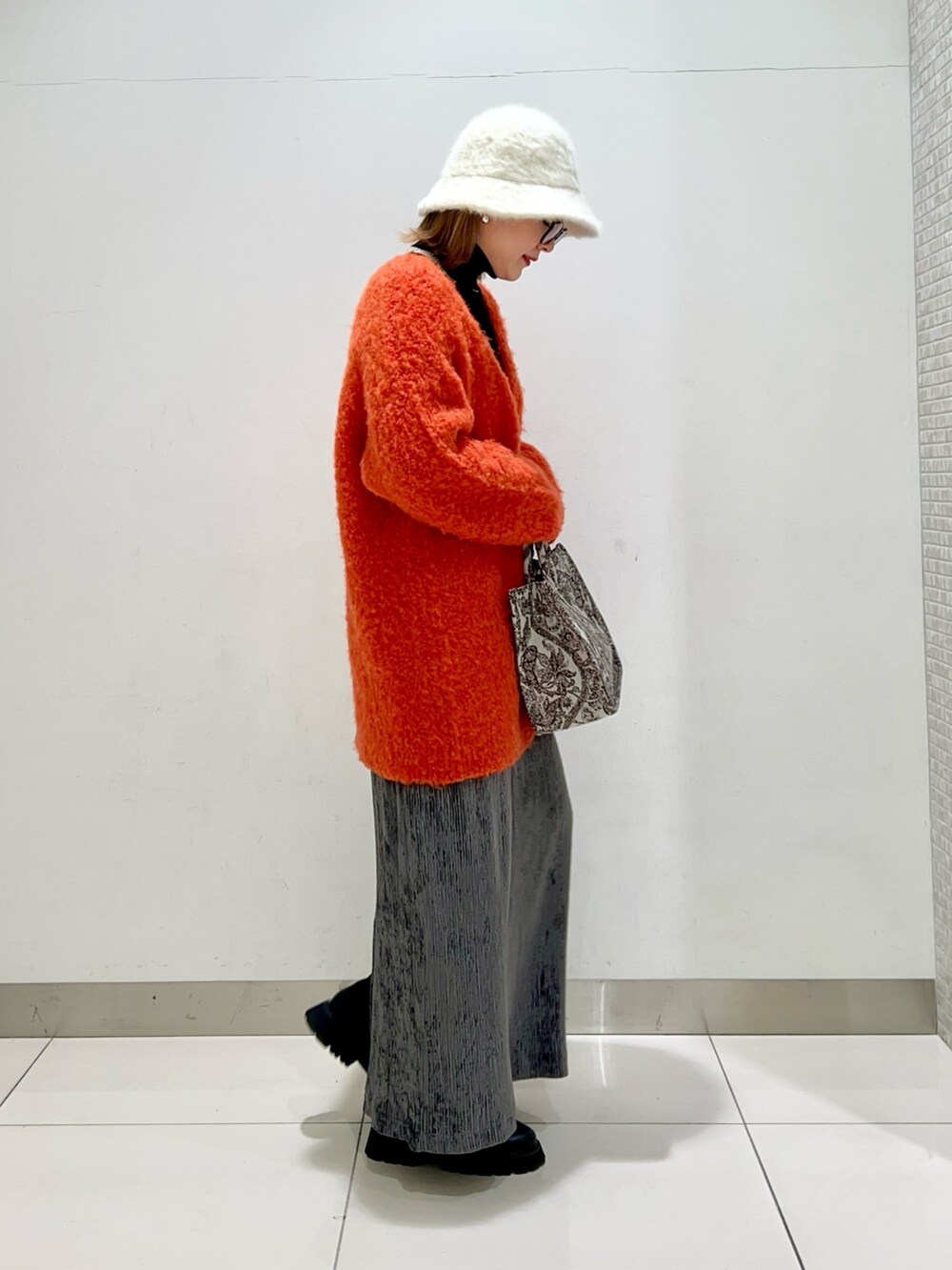 ブラック系のニット/セーター、オレンジ系のカーディガン/ボレロ、ブラウン系のトートバッグを着用したレディースの冬コーディネートの5枚目の写真