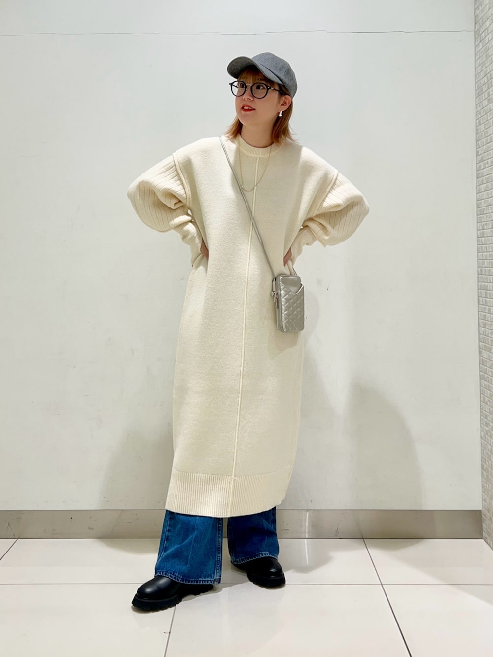 シルバー系のショルダーバッグ、ホワイト系のワンピース、ブルー系のデニムパンツを着用したレディースの冬コーディネートの7枚目の写真