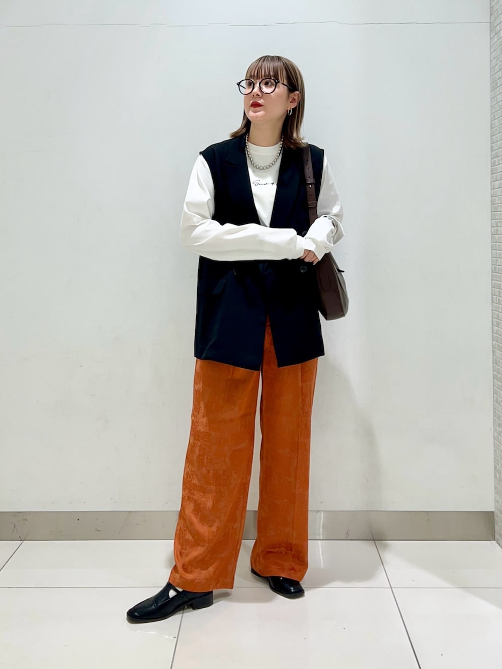ブラウン系のショルダーバッグ、ブラック系のその他アウター、オレンジ系のその他パンツを着用したレディースの春コーディネートの7枚目の写真