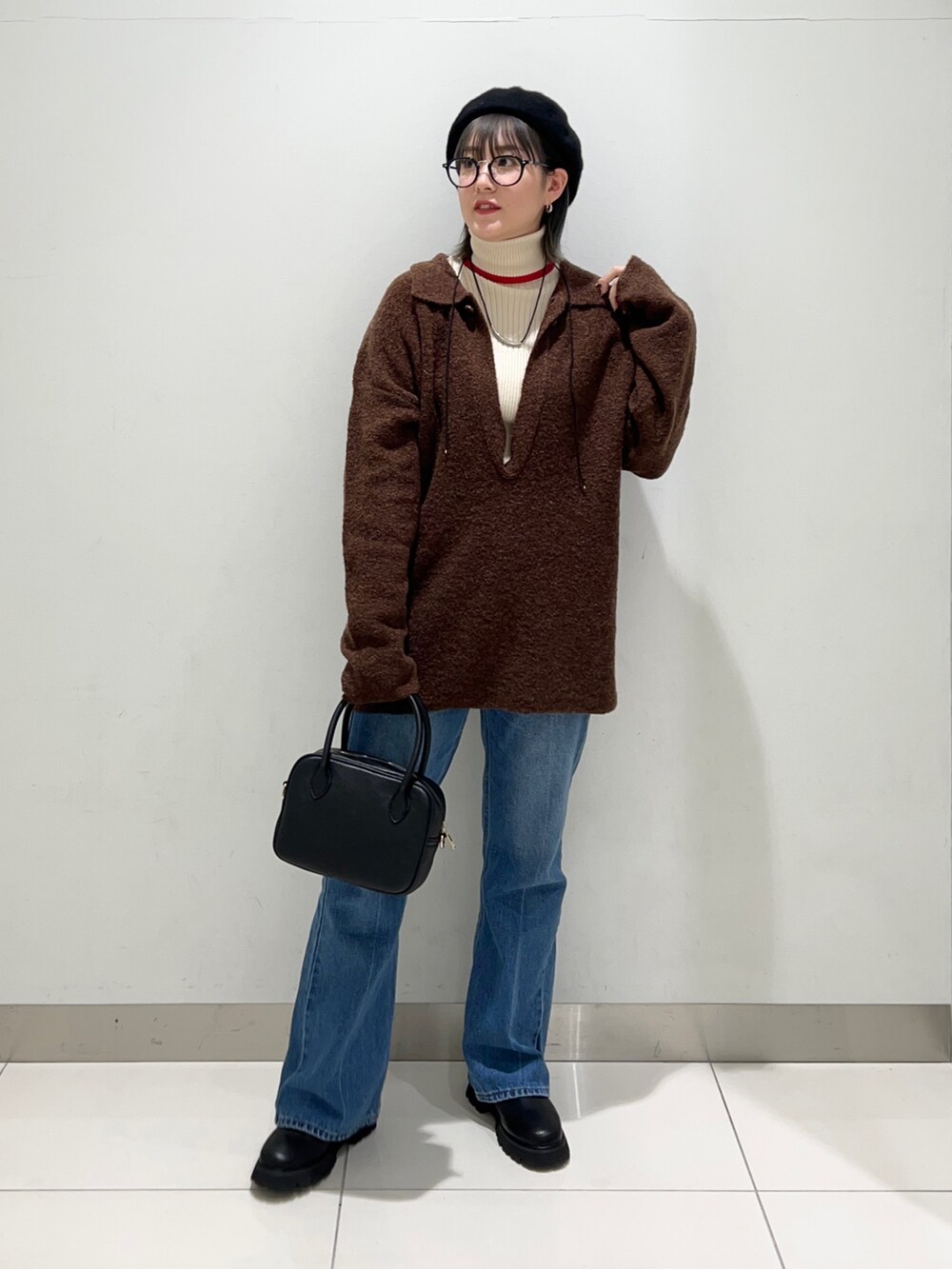 ブラック系のブーツ、ブルー系のデニムパンツ、ブラック系のボストンバッグを着用したレディースの秋コーディネートの6枚目の写真