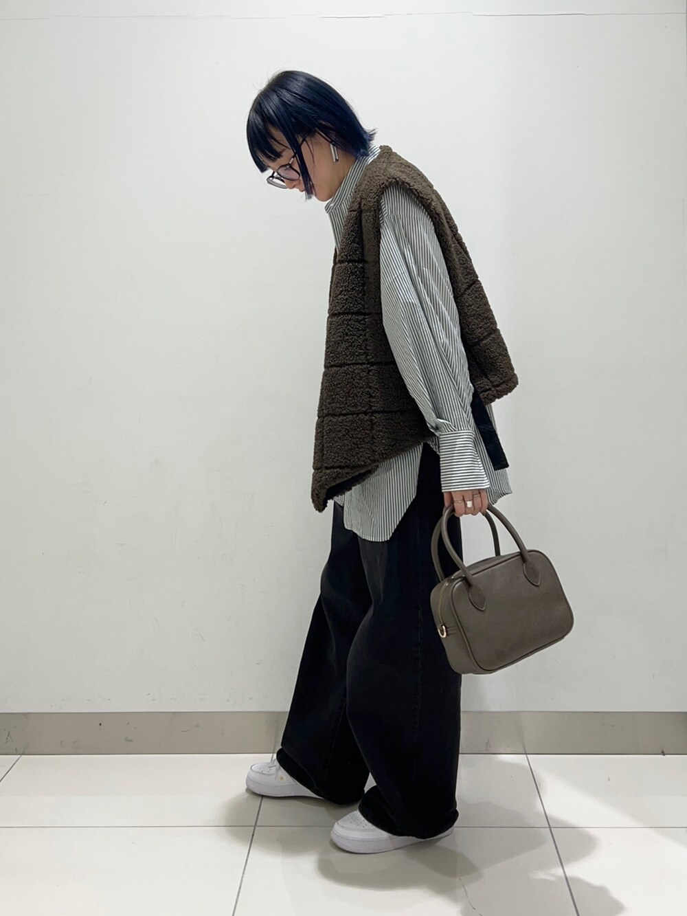 ブラック系のデニムパンツ、ブラウン系のボストンバッグ、グリーン系のシャツ/ブラウスを着用したレディースの秋コーディネートの3枚目の写真