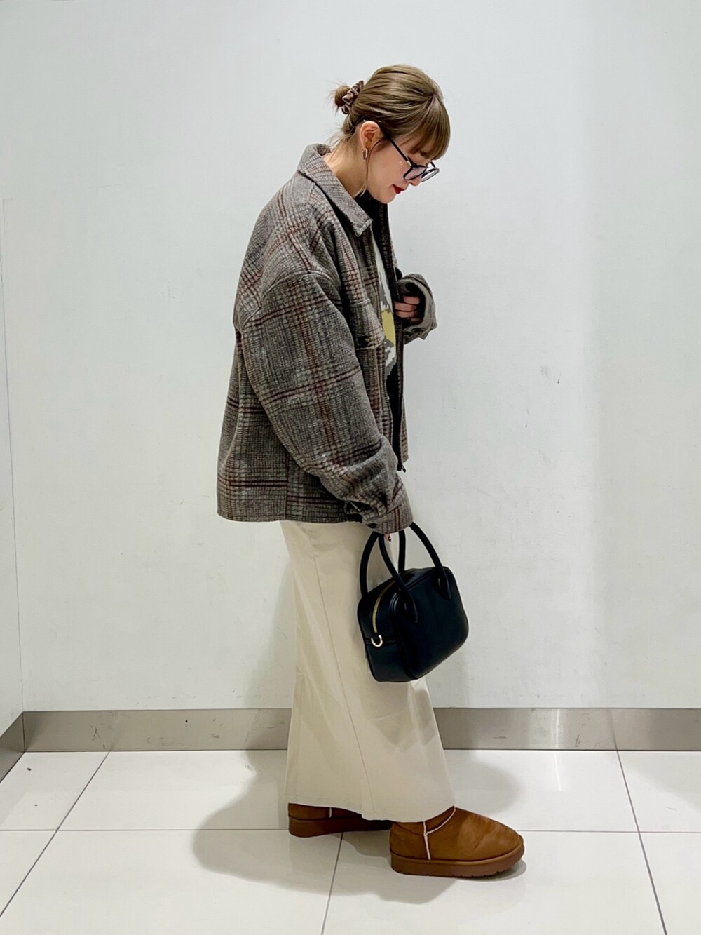 ブラック系のボストンバッグ、ベージュ系のスカート、ブラック系のニット/セーターを着用したレディースの冬コーディネートの5枚目の写真