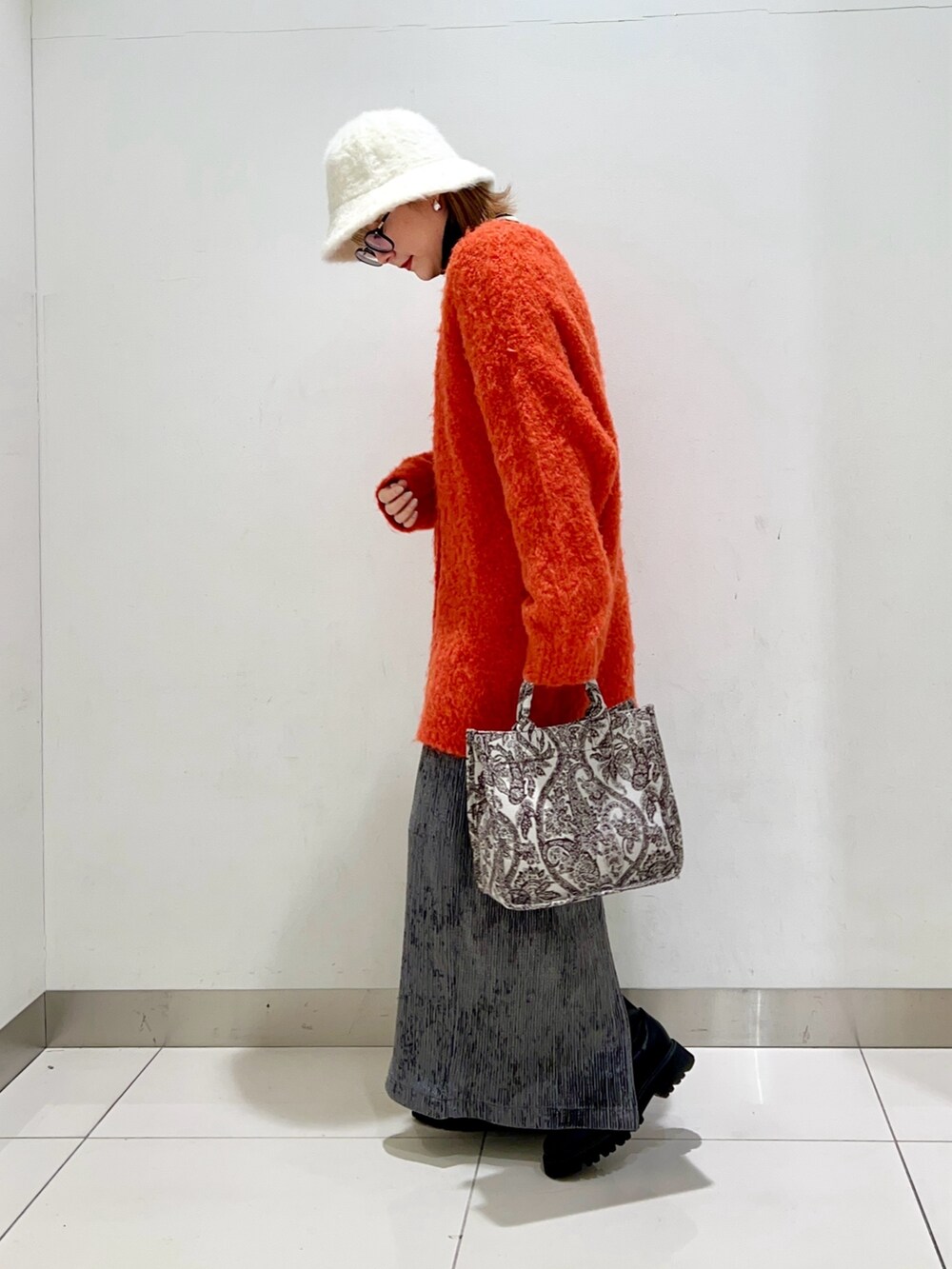 ブラック系のニット/セーター、オレンジ系のカーディガン/ボレロ、ブラウン系のトートバッグを着用したレディースの冬コーディネートの3枚目の写真