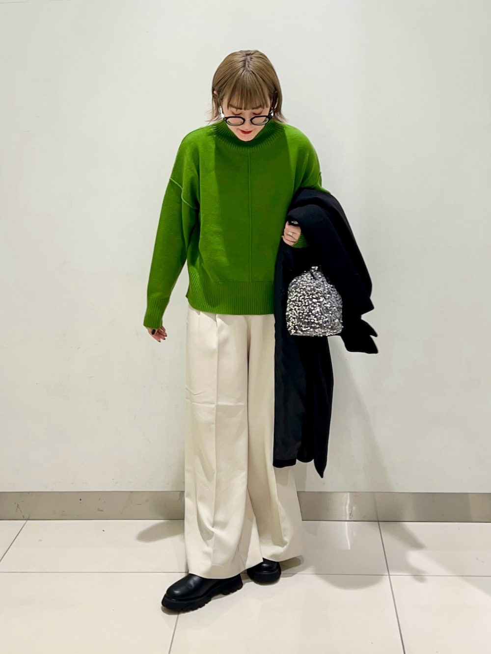 グリーン系のニット/セーター、ホワイト系のその他パンツ、ブラック系のブーツを着用したレディースの冬コーディネートの2枚目の写真