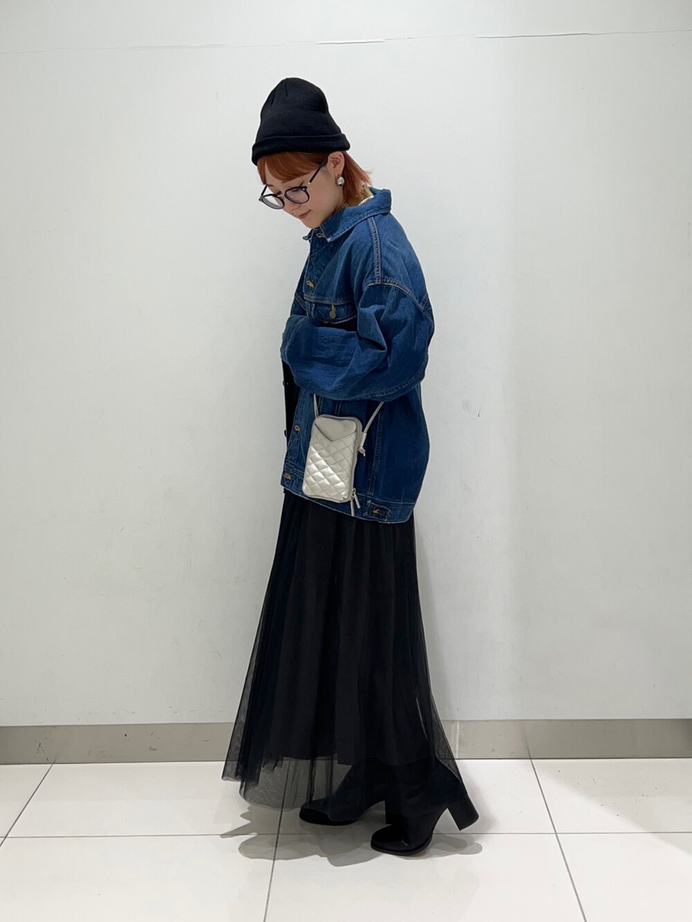 ブラック系のスカート、ブルー系のデニムジャケット、イエロー系のニット/セーターを着用したレディースの秋コーディネートの3枚目の写真