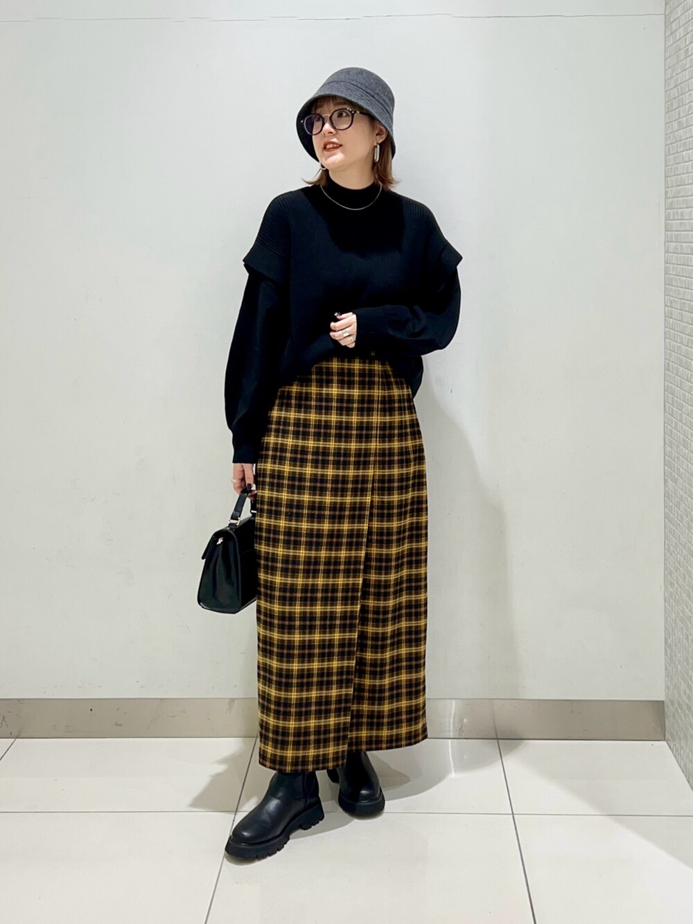ホワイト系のジャケット/アウター、ブラック系のニット/セーター、イエロー系のスカートを着用したレディースの冬コーディネートの7枚目の写真