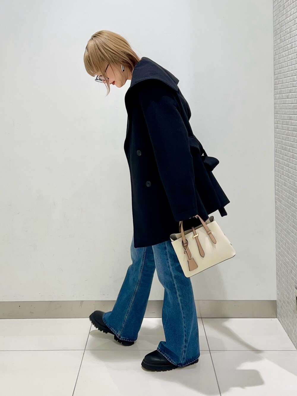 ブラック系のブーツ、ホワイト系のハンドバッグ、ブラック系のその他アウターを着用したレディースの冬コーディネートの3枚目の写真