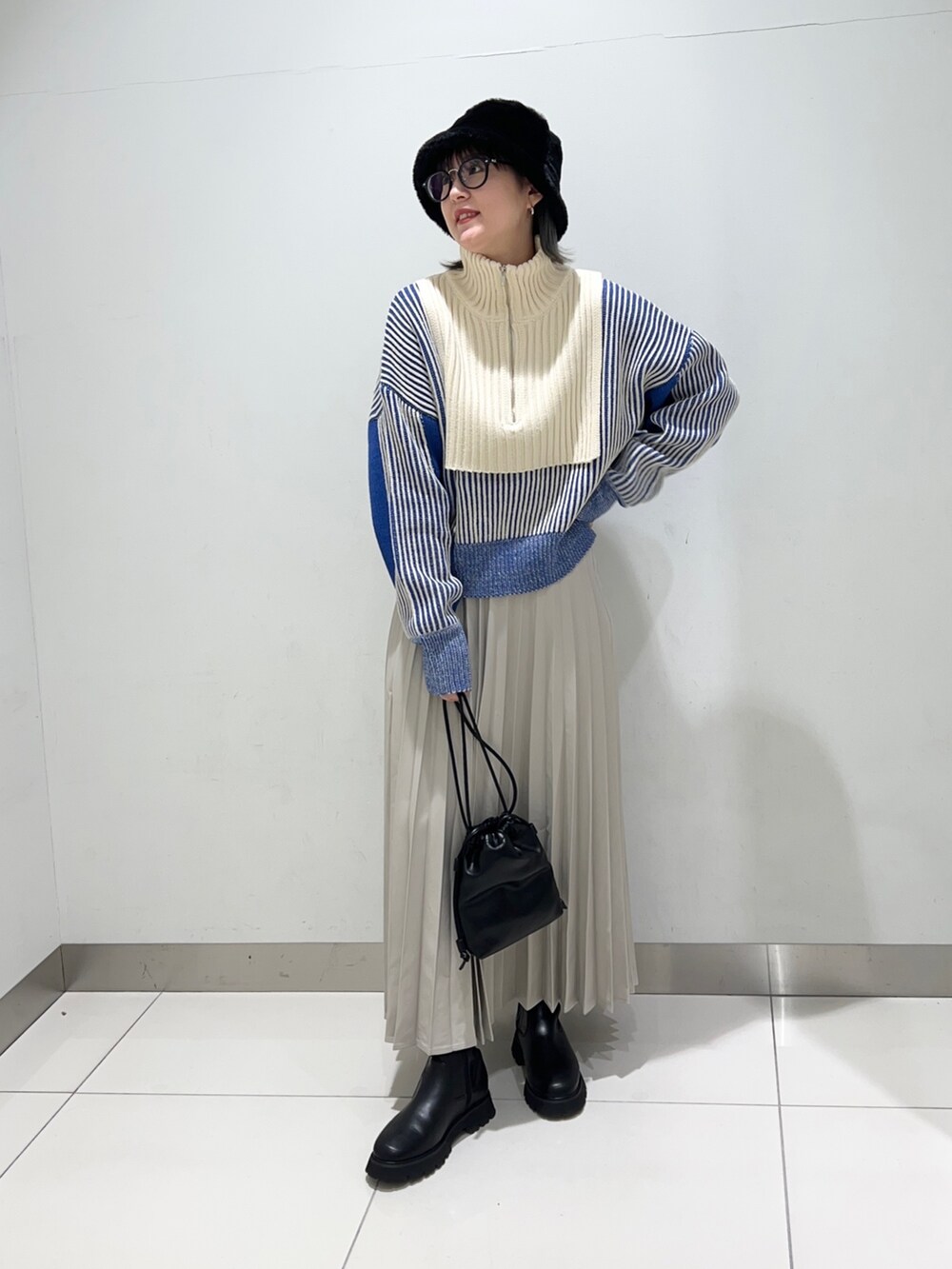 ベージュ系のスカート、ブラック系のショルダーバッグ、ブラック系のブーツを着用したレディースの秋コーディネートの2枚目の写真