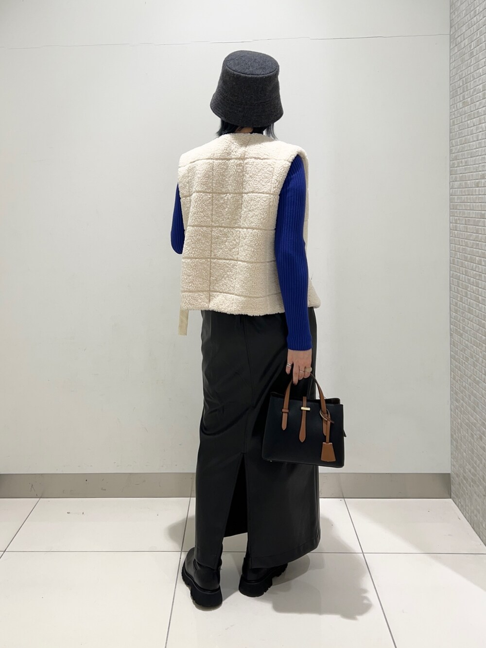 ホワイト系のベスト、ブラック系のスカート、ブルー系のニット/セーターを着用したレディースの秋コーディネートの4枚目の写真