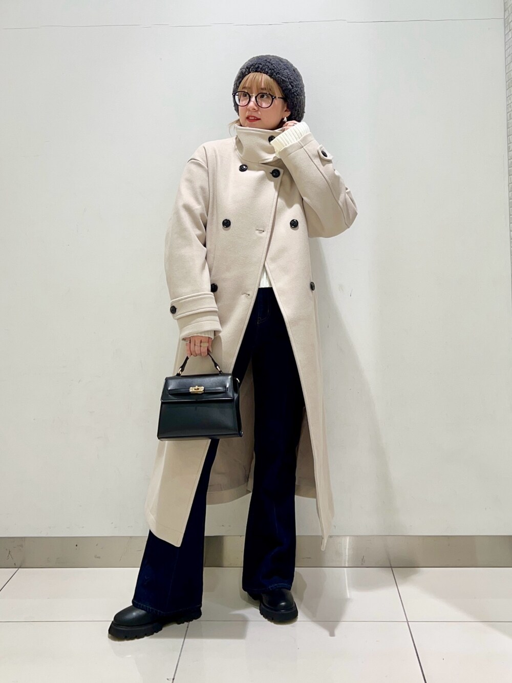 ベージュ系のステンカラーコート、ブルー系のデニムパンツ、ブラック系のショルダーバッグを着用したレディースの冬コーディネートの6枚目の写真