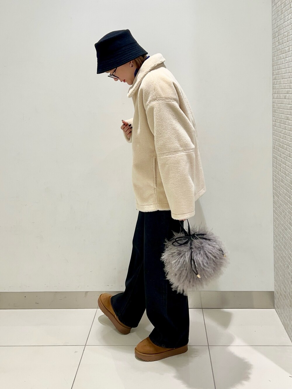 ブラック系のデニムパンツ、ブルー系のニット/セーター、ホワイト系のブルゾンを着用したレディースの冬コーディネートの3枚目の写真