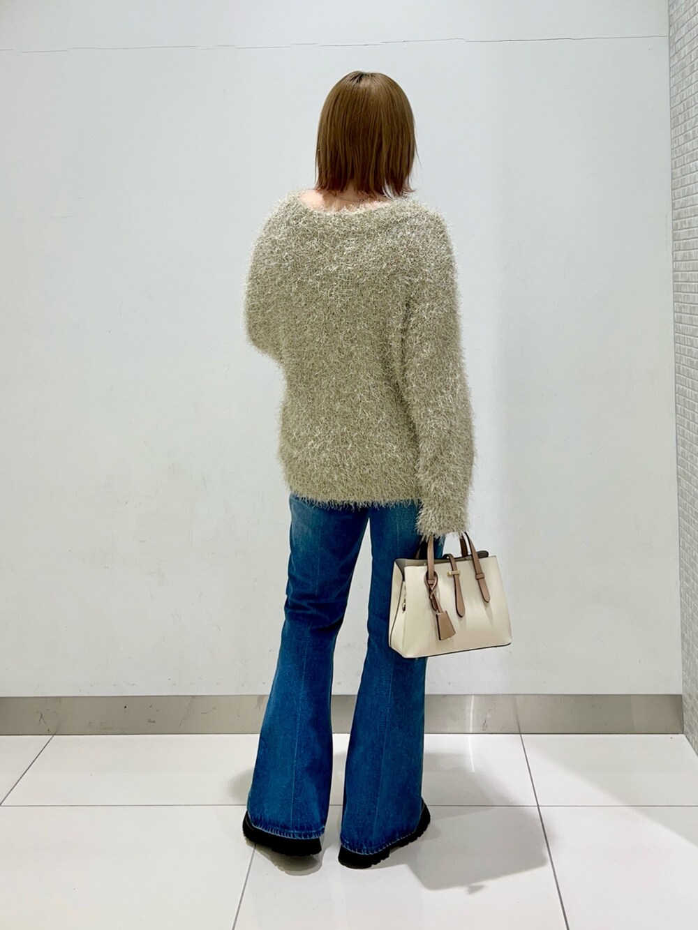 ブラック系のブーツ、ホワイト系のハンドバッグ、ブラック系のその他アウターを着用したレディースの冬コーディネートの9枚目の写真