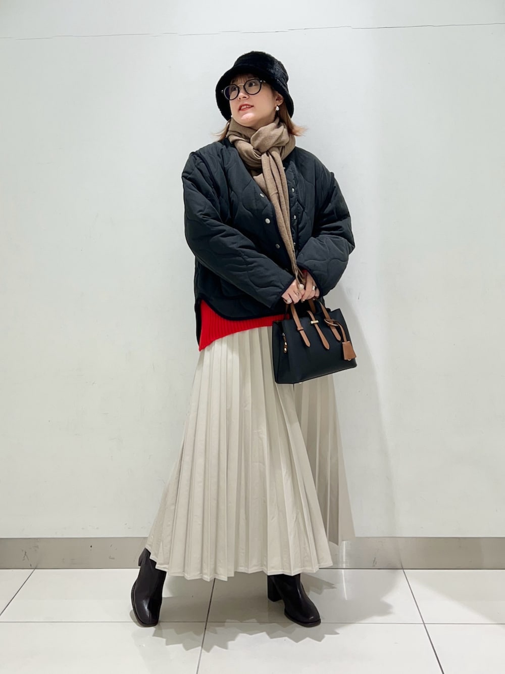 ブラウン系のブーツ、ベージュ系のスカート、ブラック系のハンドバッグを着用したレディースの冬コーディネートの8枚目の写真